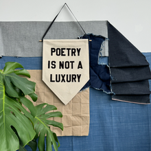 Load image into Gallery viewer, Textile wall art with 'Poetry is not a luxury' quote on a canv as pennant